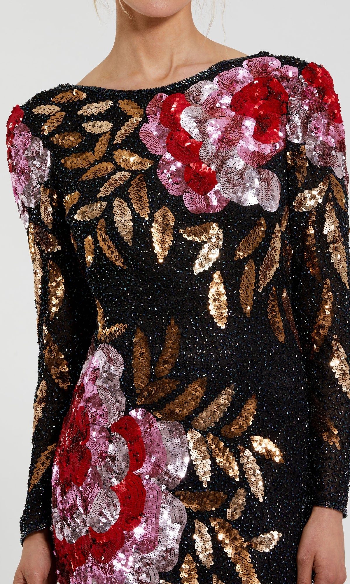 A person wearing the Mac Duggal 4566 Long Sleeve Sequin Formal Gown, a black evening dress adorned with large red and pink sequin flowers and gold sequin leaves.